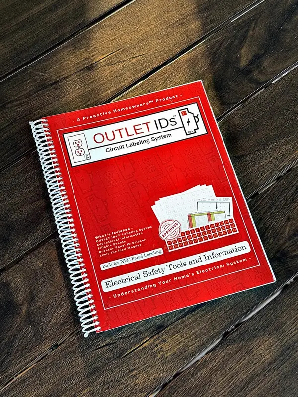 The red spiral-bound OUTLET IDs Circuit Labeling System book on a wooden table